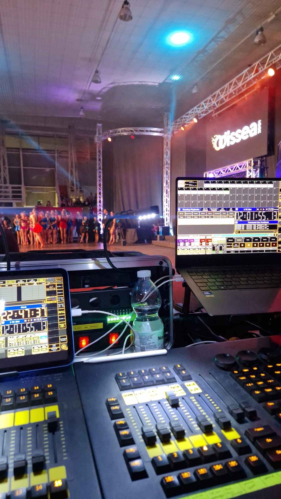 Postazione di controllo luci con il palco e gli artisti sullo sfondo